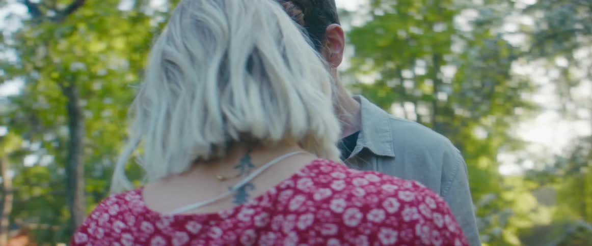 A couple embraces while holding hands outdoors