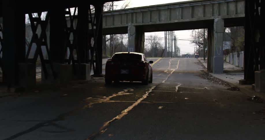 Car driving under a bridge on a small town street at evening