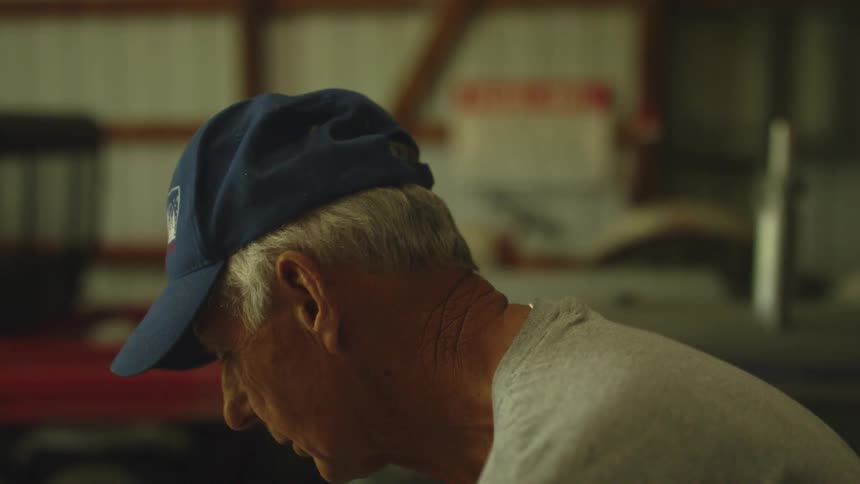 An elderly man bends down as he concentrates on something