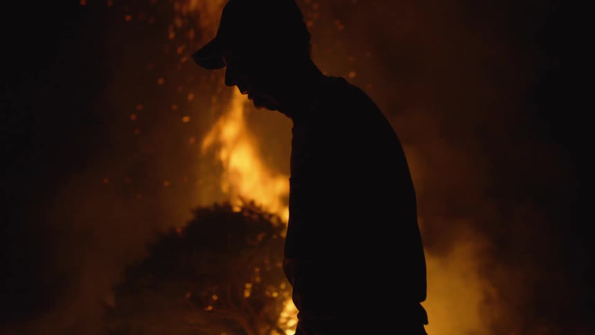 A man throws a branch into the fire