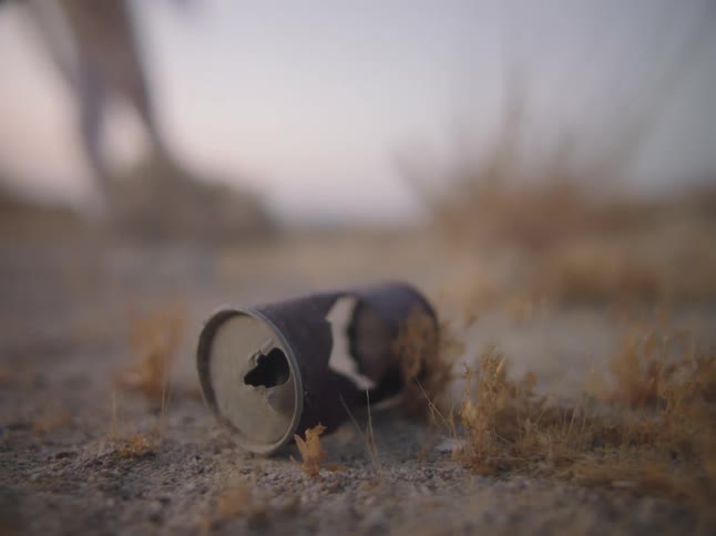 A can on the ground with a person the sky and clouds in the background