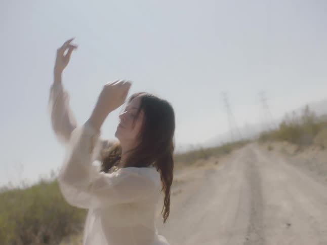 A woman dances on a road in a rural area