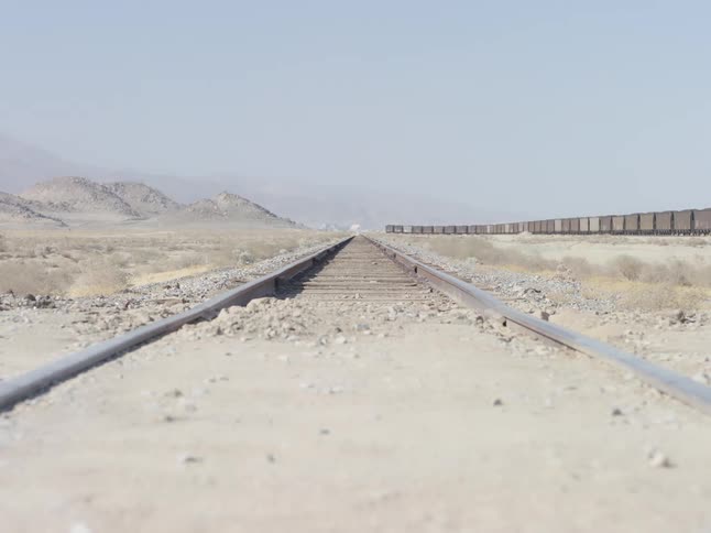Wide shot of a railway track with a freight train visible in the background