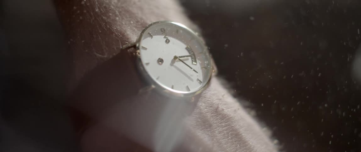 Sawdust flies past a watch on a man's wrist