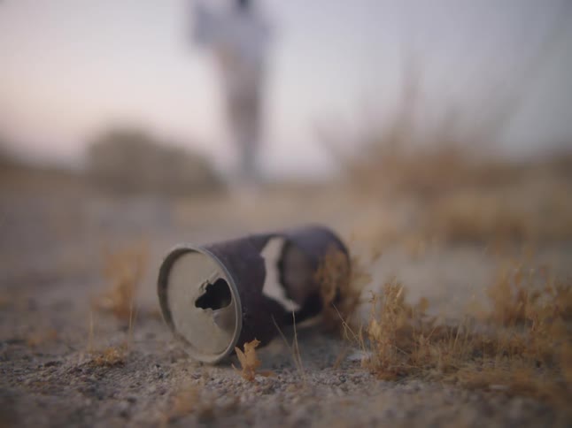 A can on the ground with a person the sky and clouds in the background