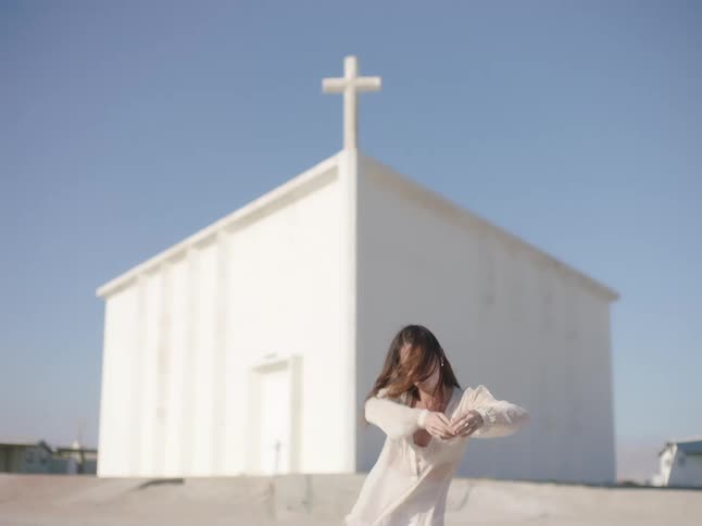 A woman dancing outdoors in front of a church