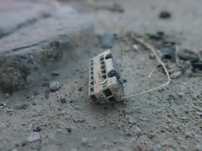 A discarded and dirty toy bus sits in gravel