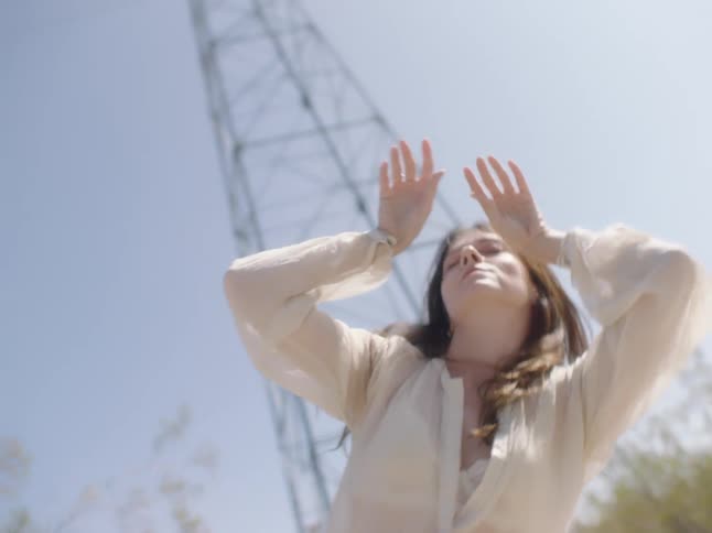 A woman is dancing outdoors in what seems to be a countryside area