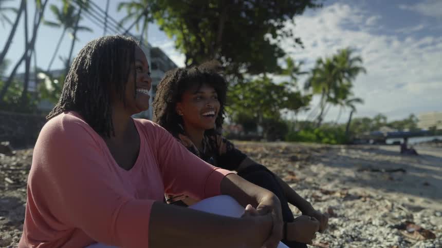 Two women laugh and talk on the beach