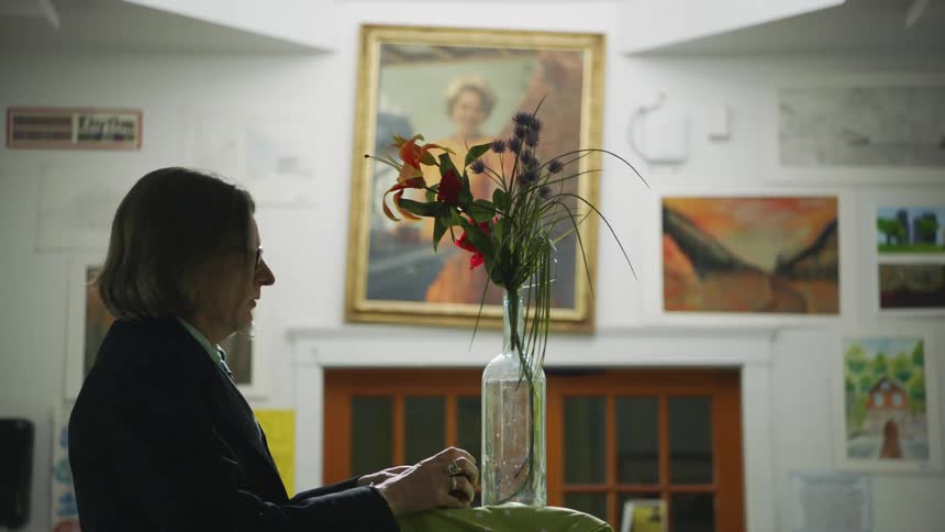 A man arranges wildflowers in a vase in an art classroom