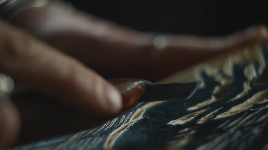 A person carving into wood with a tool