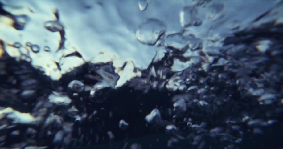 Waves move up and down in the ocean near a mountain range