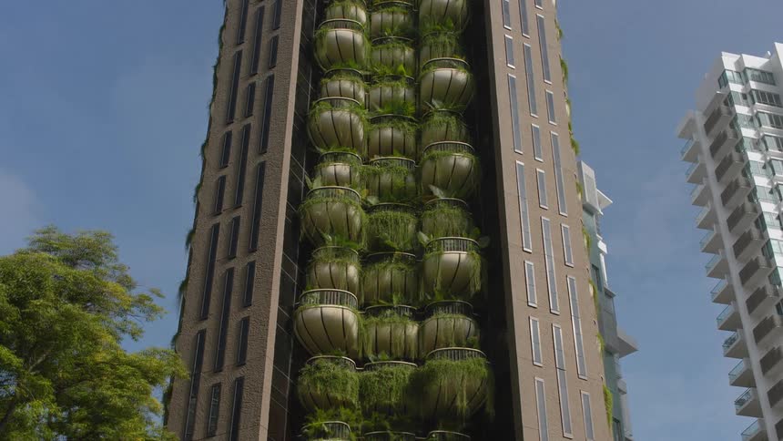 A time lapse of a building outdoors with lush plants growing on its many balconies