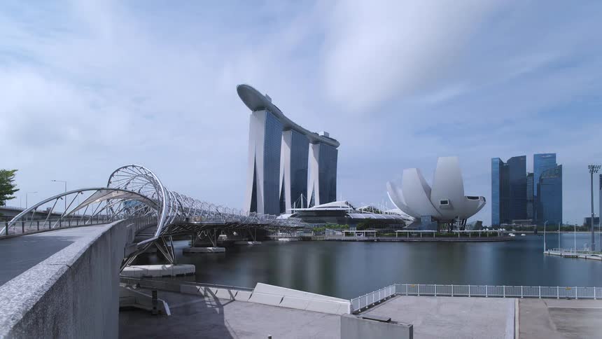 A river with a bridge with buildings the sky and clouds in the background speeding up