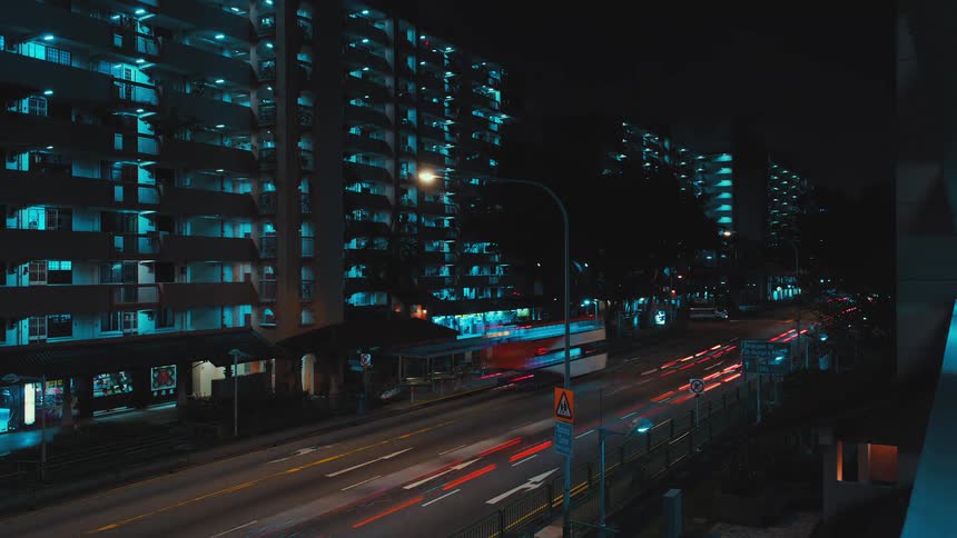 Cars and buses travel on a city highway blur and glow at night