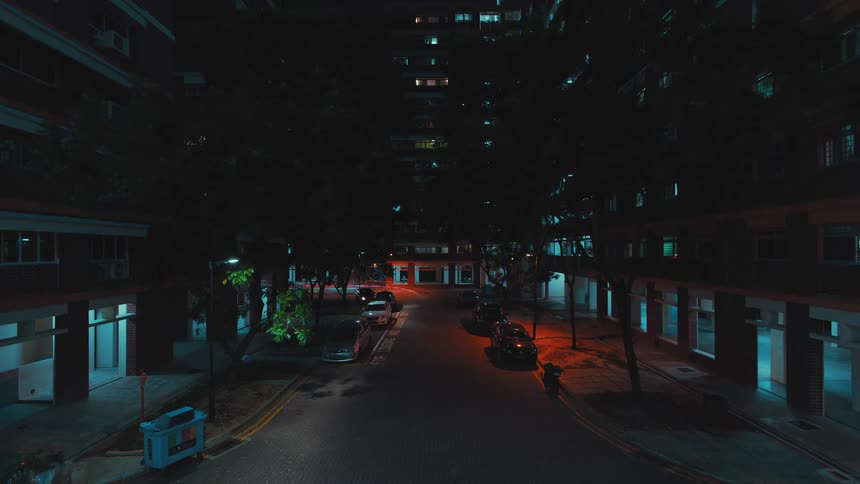 A vehicle weaves past vehicles parked on the street outside parking garages and apartment buildings