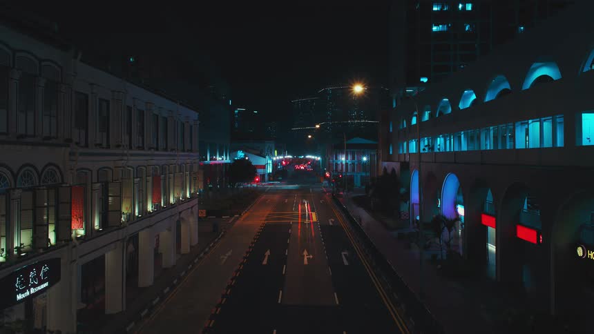 People and vehicles go down a one way road past apartment buildings in a city