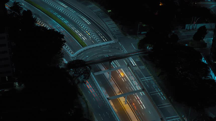 Heavy traffic drives down a freeway in a city at night