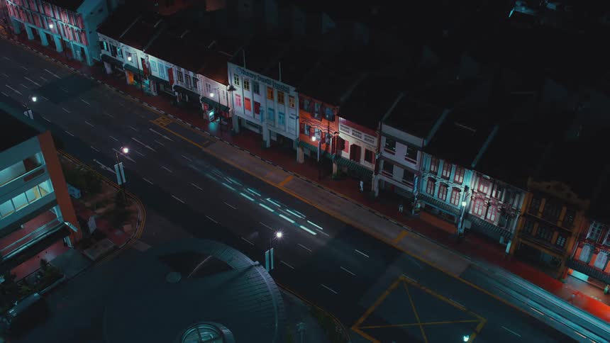 Traffic passes by as a city bus drops off and picks up passengers along a block of apartments