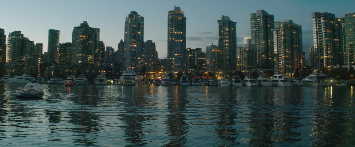 A view of Vancouver sky scrapers next to water in False Creek at dusk