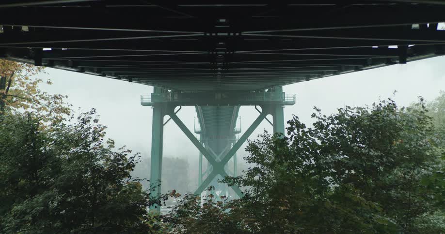 Heavy fog rises from under a green bridge