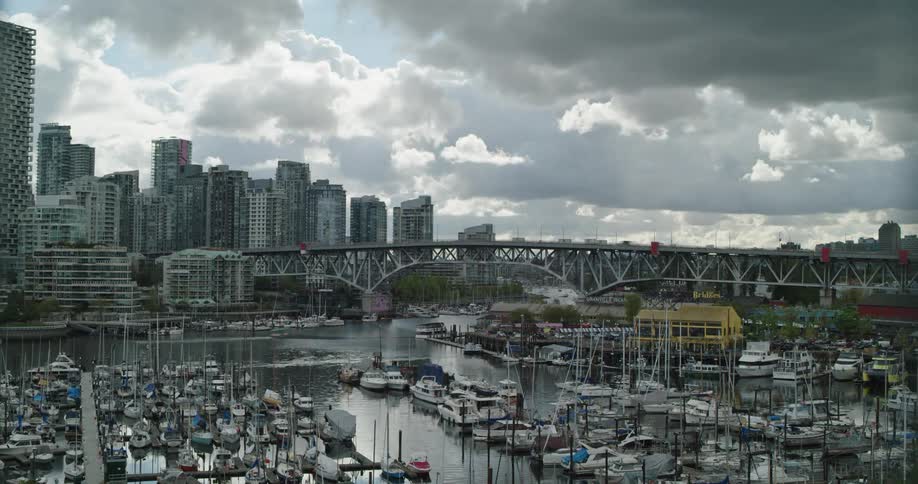 A time lapse of a waterway next to a large city shows multiple boats passing by