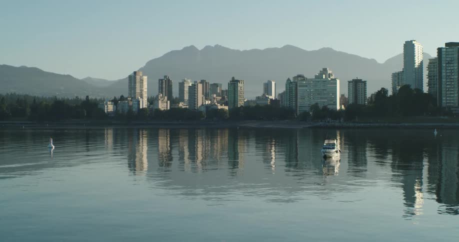 Mountains sit behind a Vancouver city skyline that's reflected in the water