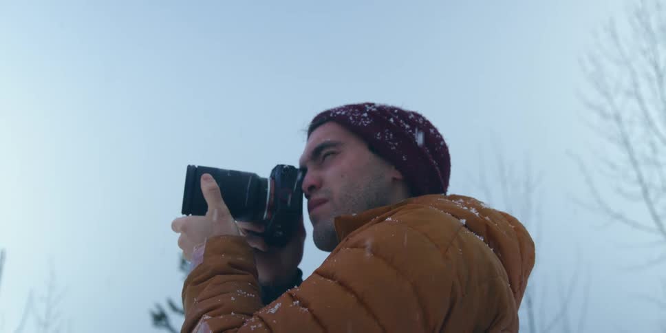 A man taking photos with a camera in the snow