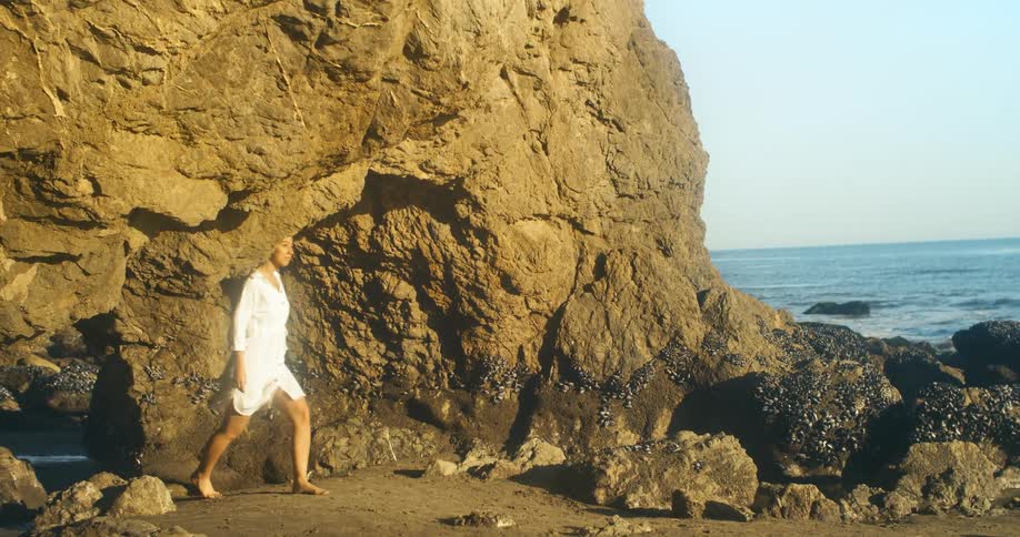 A woman walking onto a rocky beach