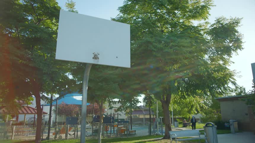 The net is missing from a basketball backboard at a park
