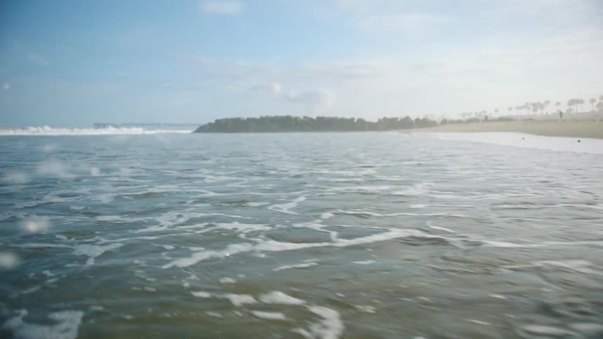 A beach with sand with the ocean sky and clouds in the background