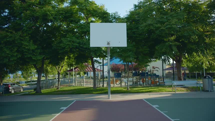 A basketball court and playground sit empty on a sunny clear day