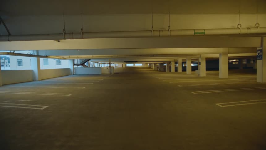 An empty parking structure has multiple rows of unoccupied parking spaces