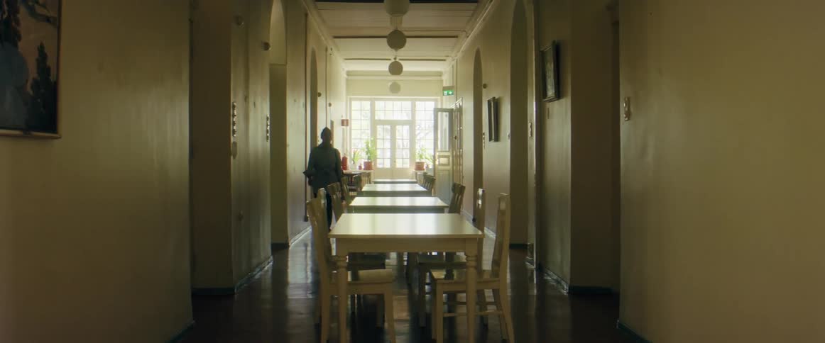 A woman is walking down a hallway of a building