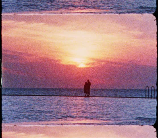 A woman swims in an infinity pool as two people along the ledge
