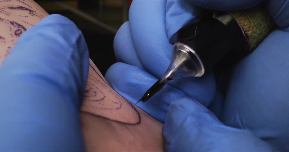 Artist creates a tattoo with a tattoo machine over the skin of a client