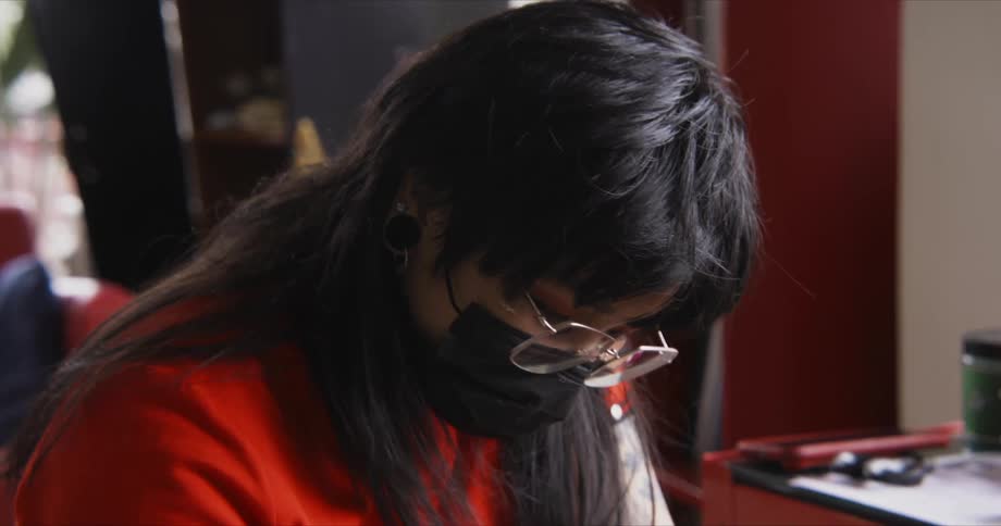 A tattoo artist looks at the arm of a person sitting in front of her