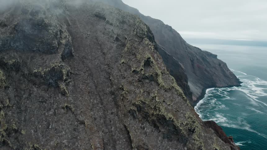 Aerial view of ocean waves crashing on the coastline of a promontory