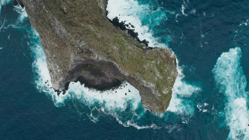 A rock headland juts into the ocean during the day
