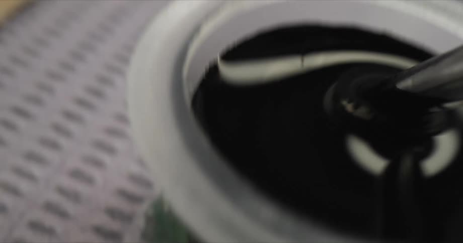 A piece of plastic being dipped into a black liquid