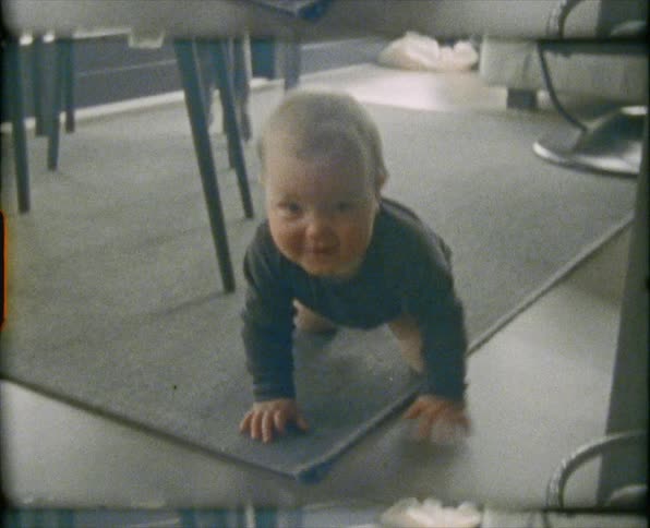 A baby boy crawls on a run under a dining room table