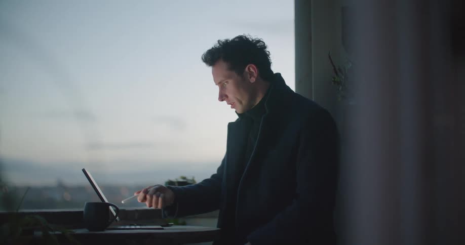 A man is sitting at a table and using a laptop