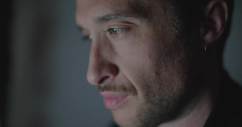Man with black t shirt and earring looks at tablet screen