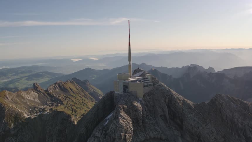 Transmission tower on top of a mountain with the sun shining brightly upon it