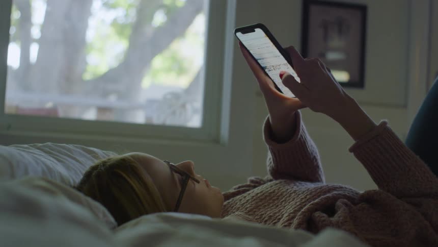 A woman using her cell phone in bed