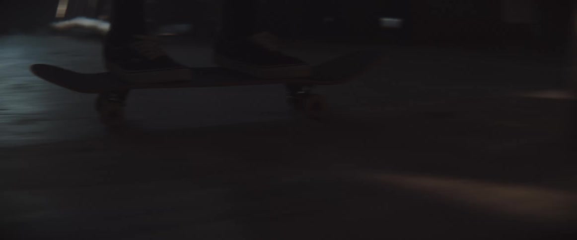 A teenager rides a skateboard through a crowded warehouse