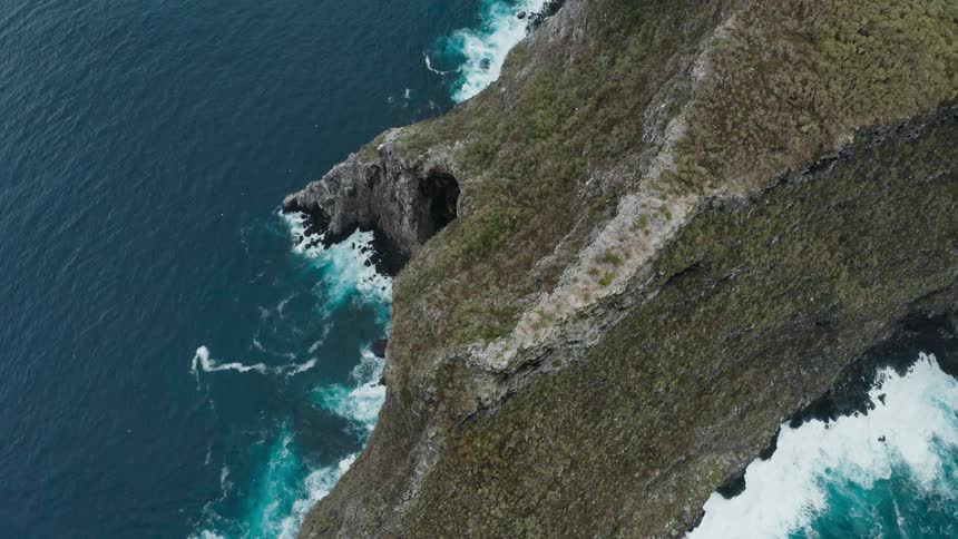 Waves pound against sheer shore topped with plateau