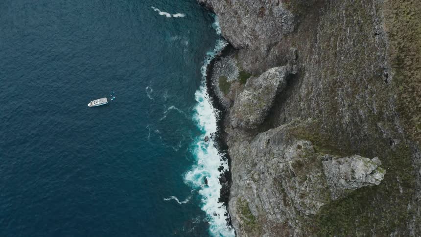 Ocean waves break against the tall rocky cliffs that form this coastline