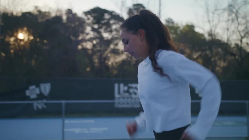Woman dribbles a soccer ball down a court before kicking it into an open goal