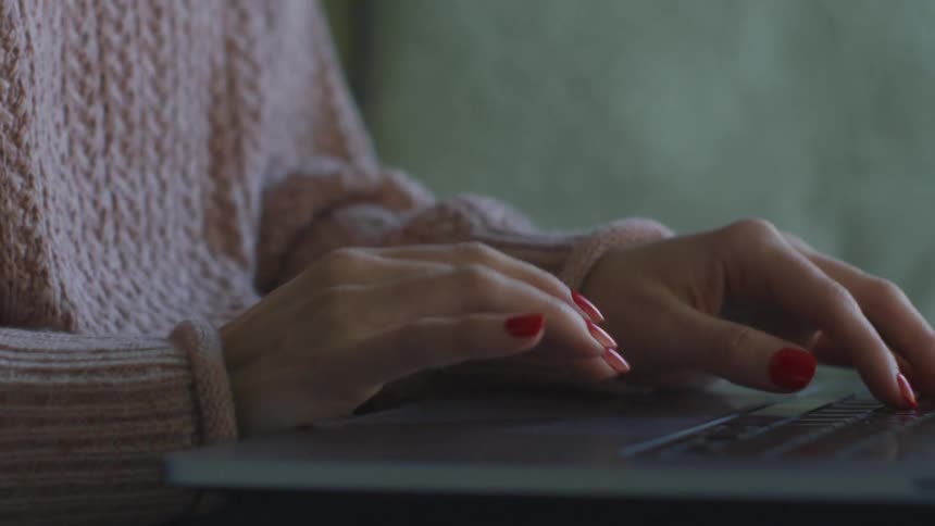 Woman scrolling on the trackpad of a laptop thats resting on her lap